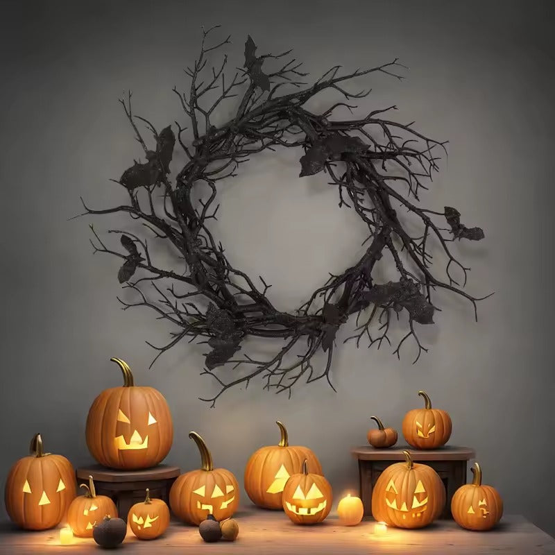Black twig bat wreath displayed above carved pumpkins